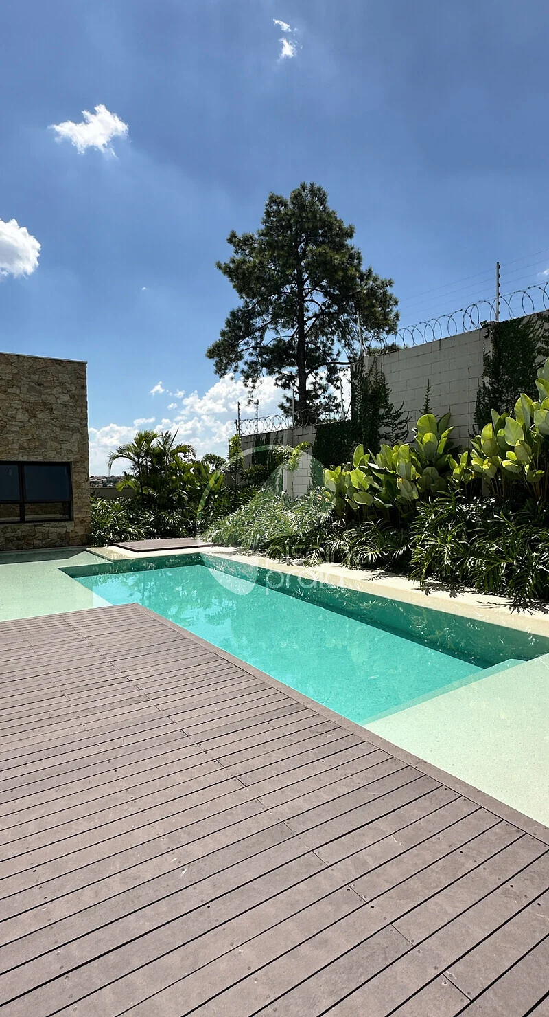 Piscina alongada com deck de madeira e vegetação ao redor