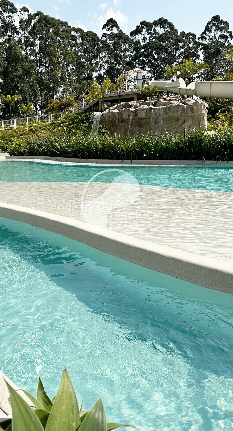 Piscina de água turquesa com prainha e jardim, vista da borda