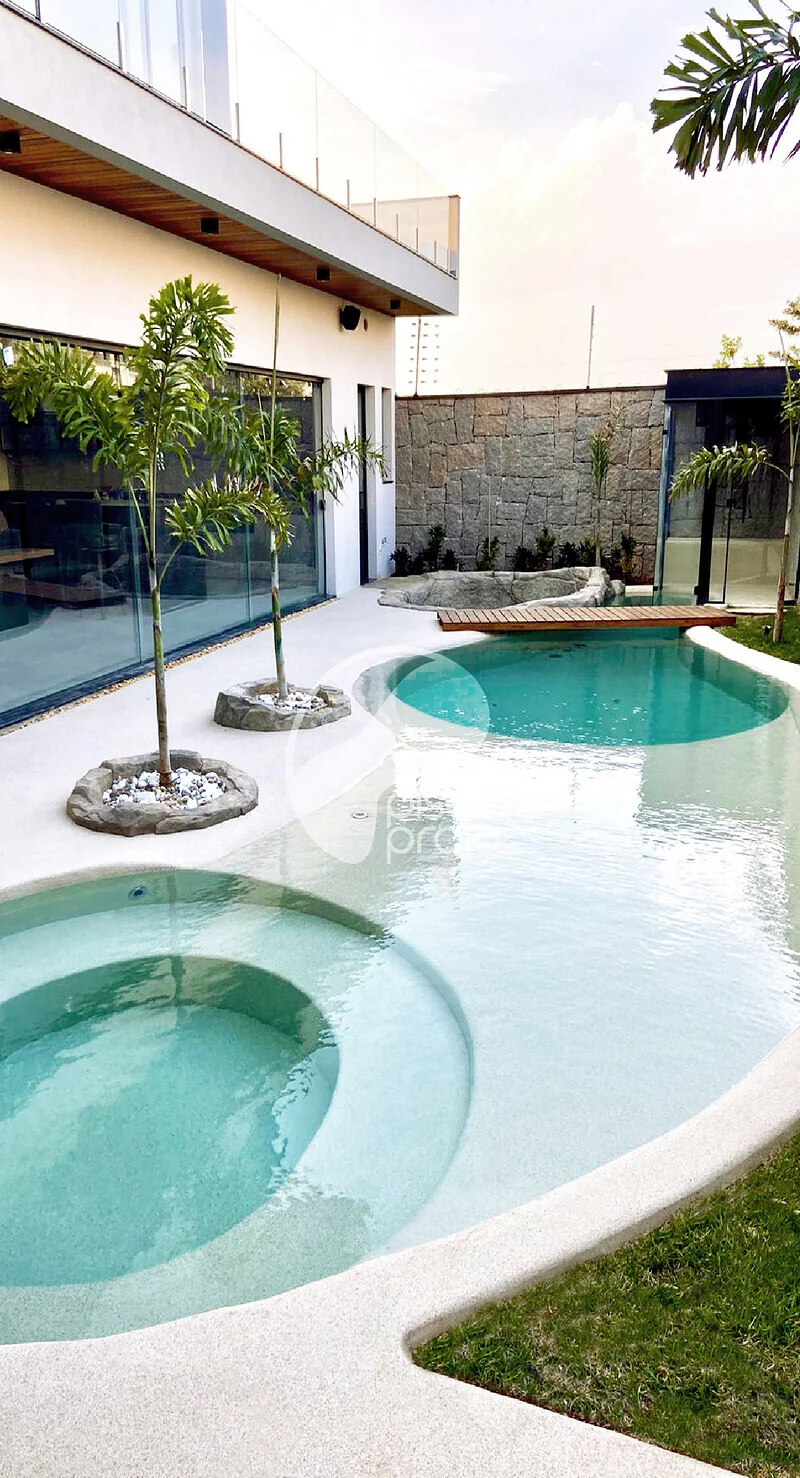 Piscina residencial com hidromassagem, ilhas de coqueiro e deck