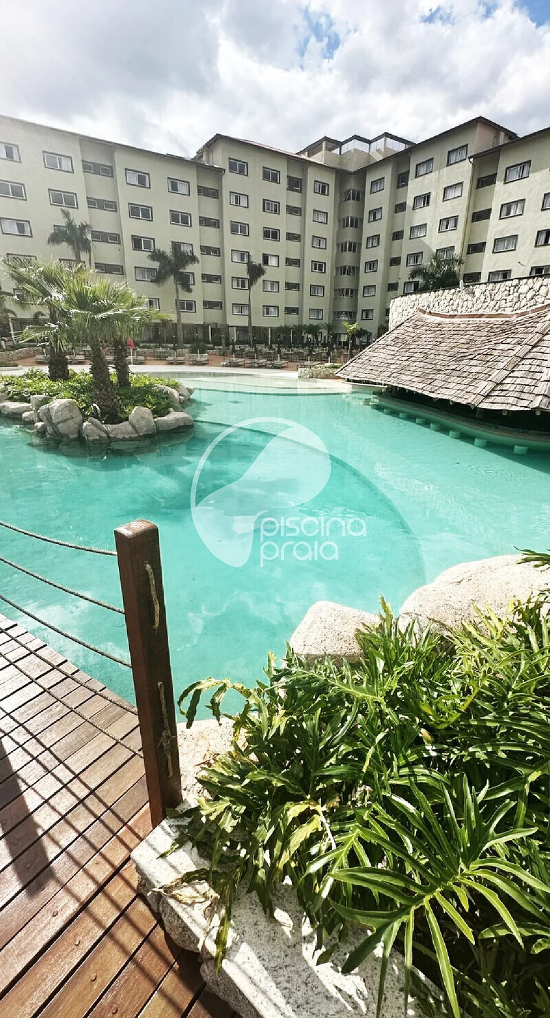 Piscina de condomínio com quiosque de palha, deck e vegetação